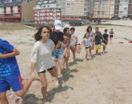 Niños en fila realizando actividad en la playa