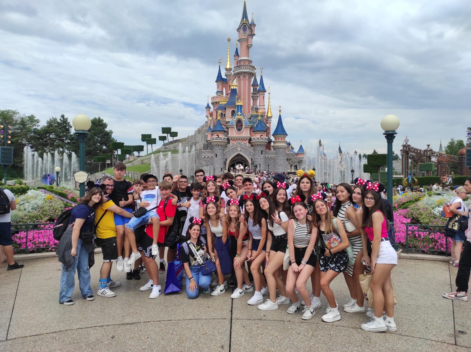 Grupo de estudiantes con orejas de minie y delante de castillo en Eurodisney