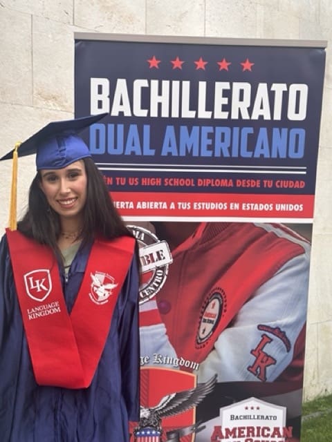 Estudiante posando delante de un cartel de BDA en su graduación en 2024