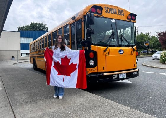 Estudiante con bandera canadiense esperando para subir al bus