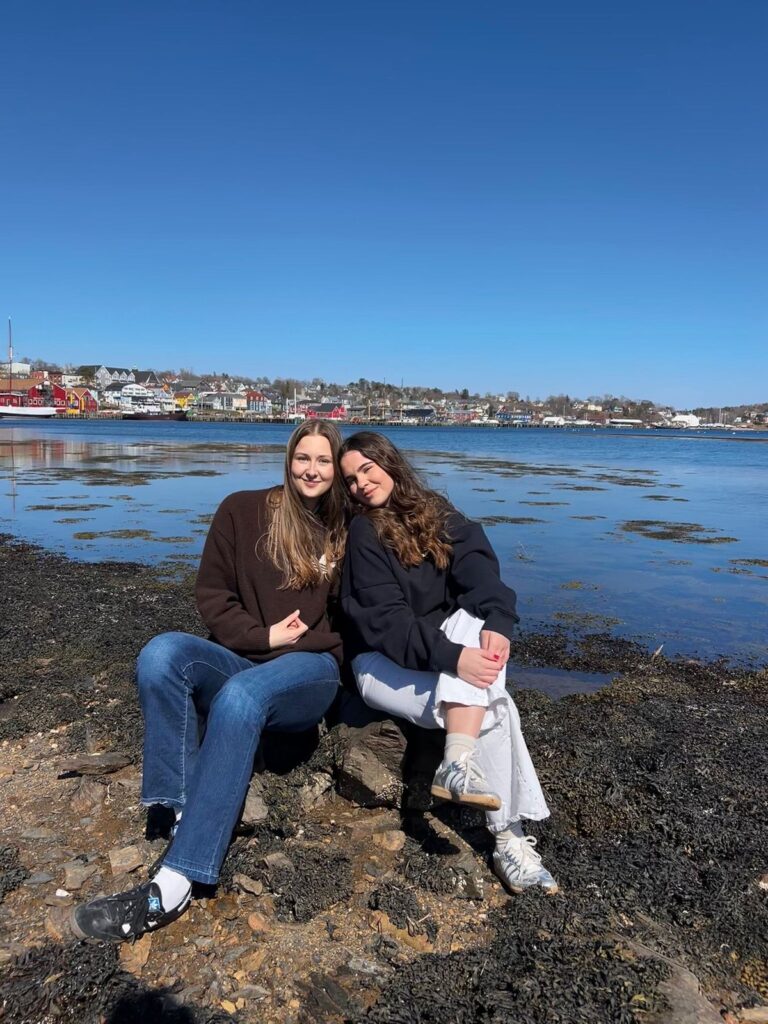 Dos estudiantes sentadas en las rocas de la costa durante una excursión en Canadá