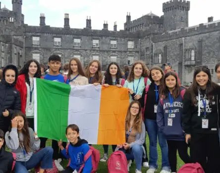 Chicos con bandera de Irlanda delante de residencia