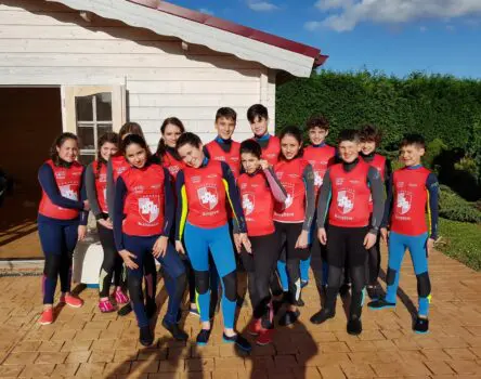 Participantes de un campamento escolar vestidos con neoprenos de surf