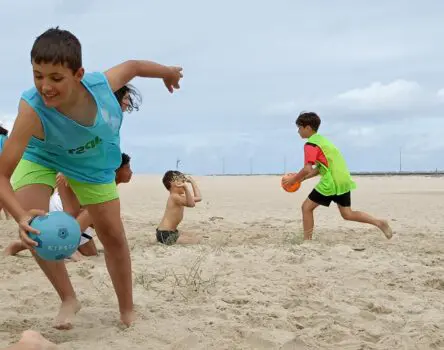 Niños jugando a la pelota en la playa en un campamento de verano en inglés en Galicia