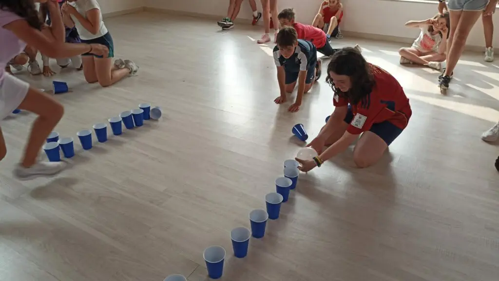 Niñas colocando vasos en el suelo en un campamento de verano en inglés en el norte de España