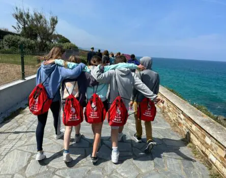 Niños entrelazando sus brazos mientras pasean con las mochilas de weekcamp