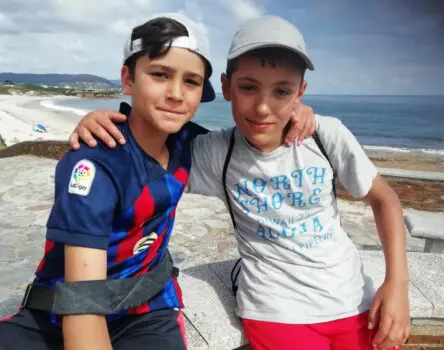 Amigos abrazados y con gorra frente al mar en el campamento de verano en inglés summercamp