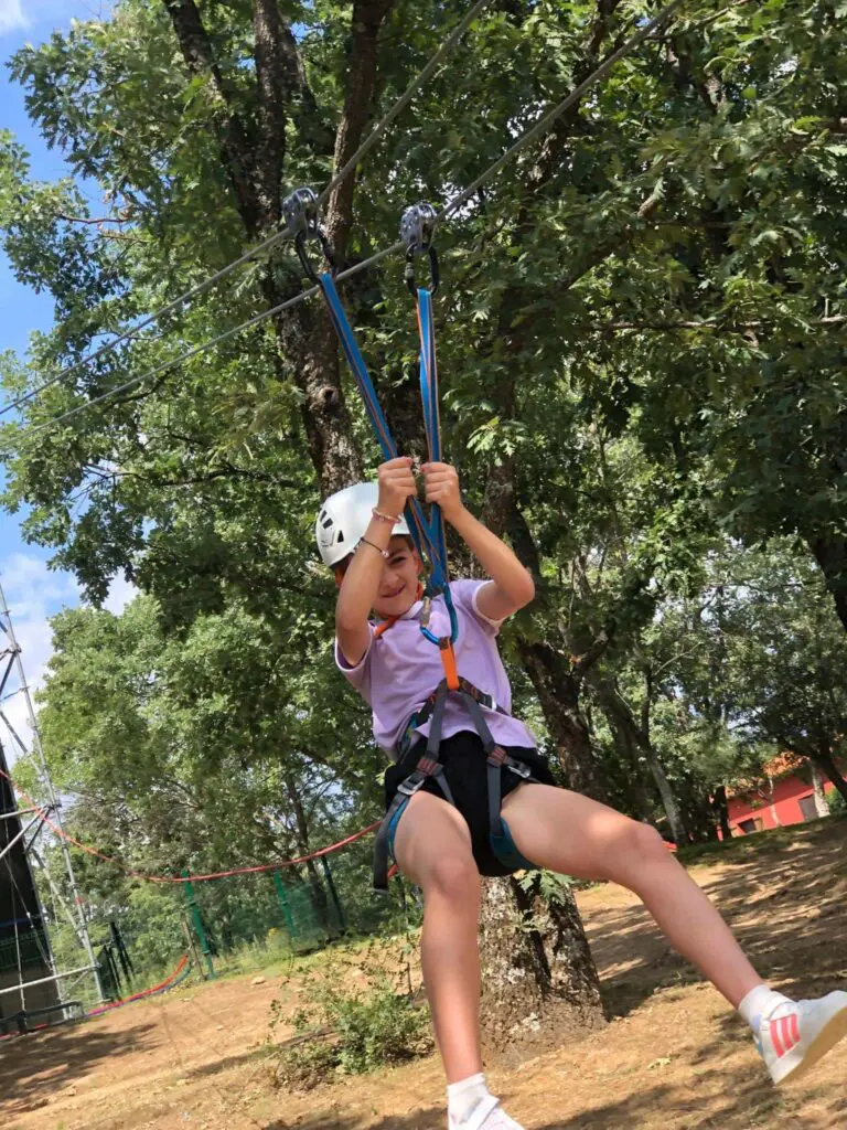 Niña haciendo actividad de tirolina en un campamento escolar en el sur de España en un campamento de veerano en inglés