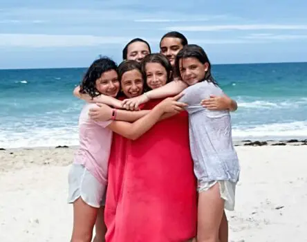 Abrazo comunitario de niñas en campamento de verano en inglés