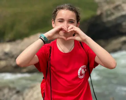 Niña haciendo símbolo de corazón con una camiseta de weekcamp