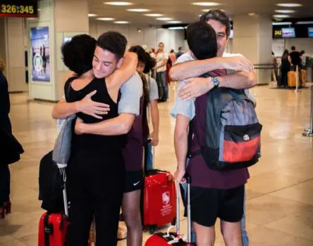 Estudiantes despidiéndose de sus padres en el aeropuerto antes de su viaje de programa académico en el extranjero