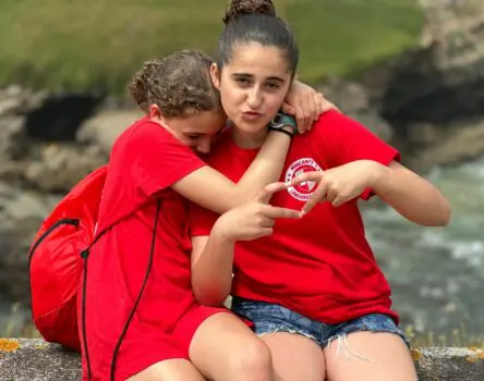 Dos amigas en un weekcamp abranzándose al aire libre