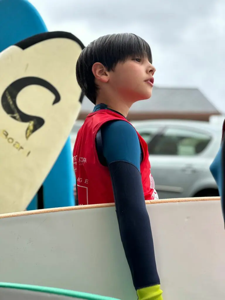 Niño con tabla preparado para surfear en el campamento educativo de Galicia