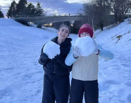 Dos chicas abrigadas y sujetando dos bolas grandes de nieve