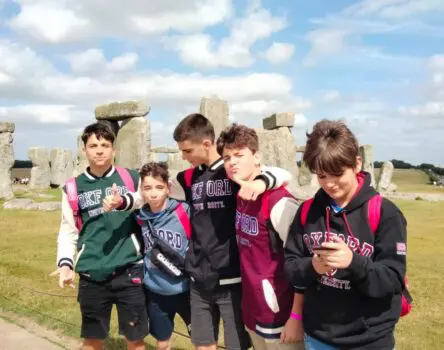 Niños con chaquetas beisboleras posando frente al Stonehenge