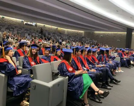 estudiantes en la graduación de BDA con su toga y birrete sentados