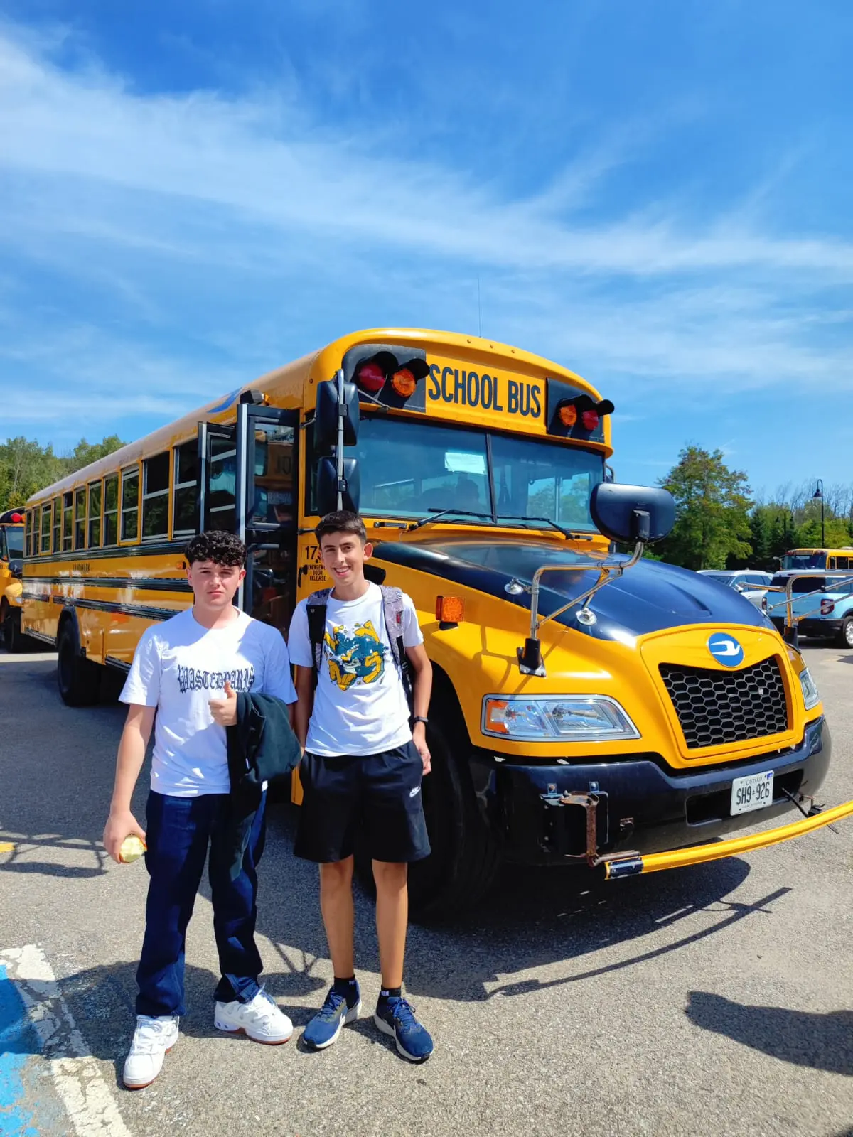 Dos estudiantes de Language Kingdom de programas académicos delante del bus escolar