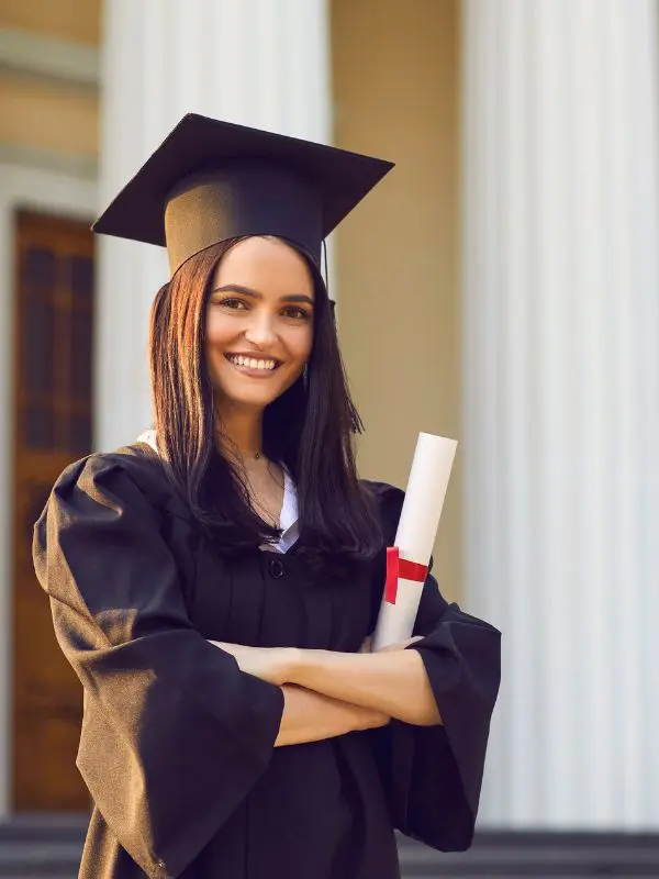 Estudiante vestida para graduación delante de su Universidad