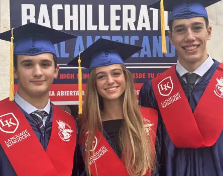 Tres estudiantes posando frente a un cartel de BDA en su graduación