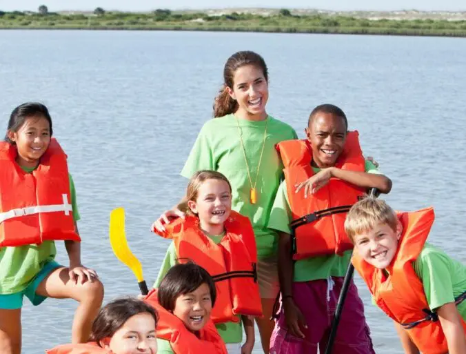 Monitora de campamento con niños en una actividad acuática