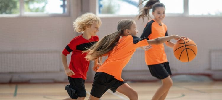 Niños jugando a baloncesto en campamento deportivo