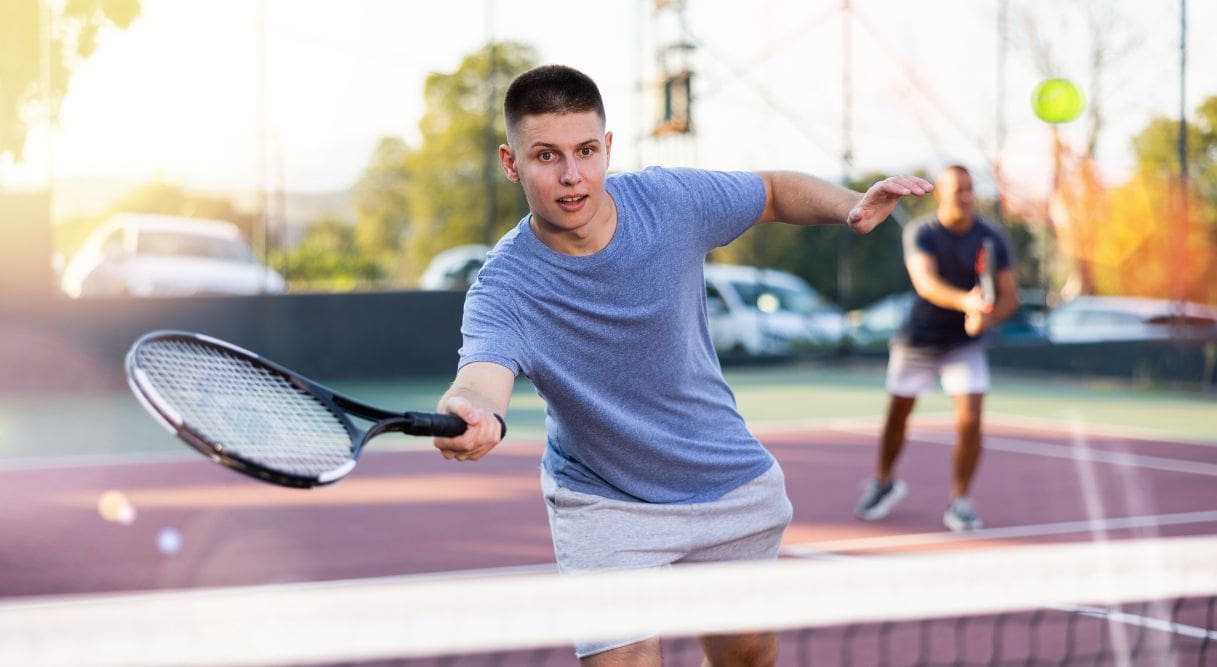 Joven jugando a tenis en una pista de uno de los campamentos deportivos