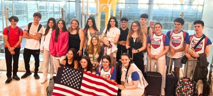 Estudiantes sujetando bandera de USA en el Aeropuerto de Barajas