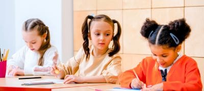 Niña mirando a una compañera de clase sentada en el pupitre