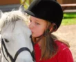 Niña dando un beso a un caballo cuando practica equitación