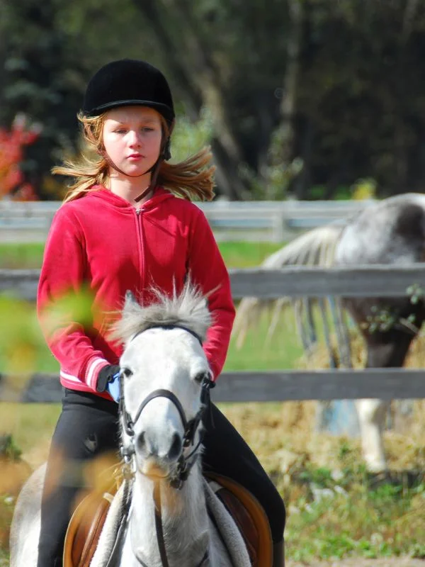 Niña montando a caballo en centro ecuestre